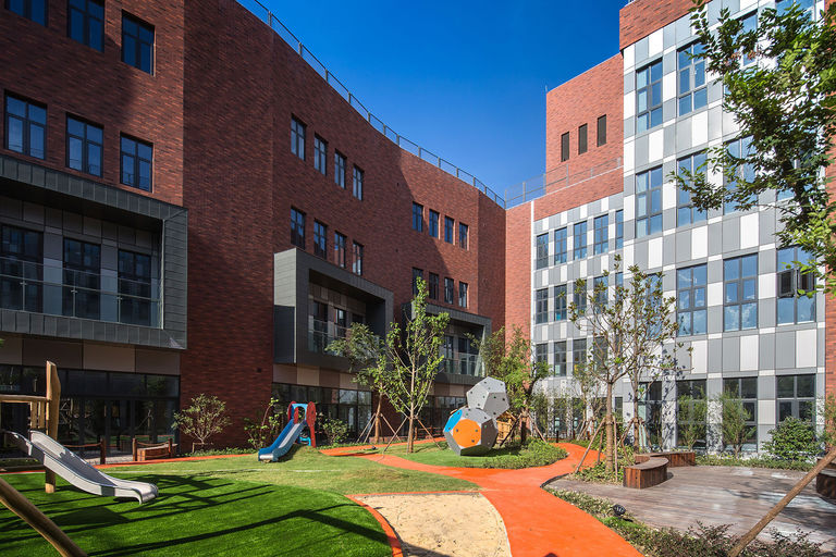 Photo of red brick façade and landscaped courtyard at the new Dulwich International School in Minhang in Shanghai, a modern interpretation of the original Dulwich College in London.