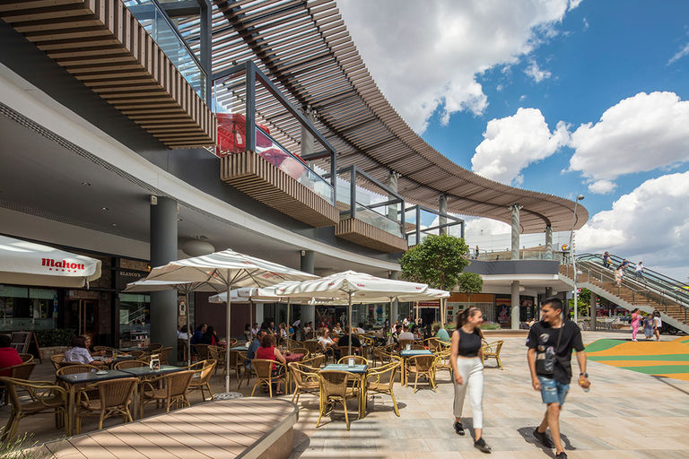 Exterior restaurant terraces and new waved canopy at Quadernillios retail centre in Alcalà de Henares, Spain.