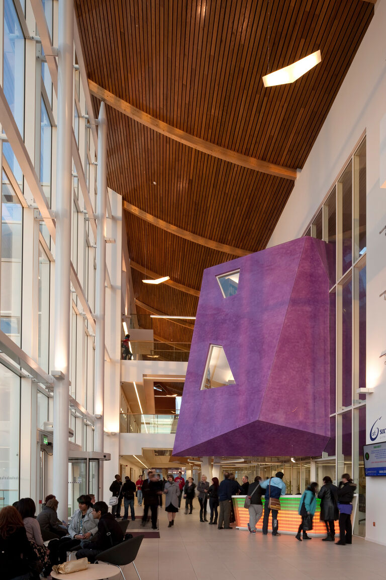 Internal photo of street style space at Stoke on Trent Sixth Form College, with brightly coloured learning pods suspended within it.