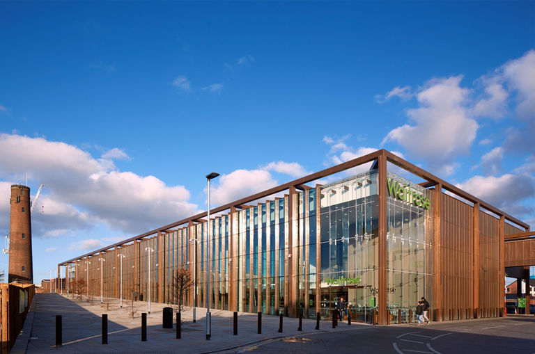 Photo showing full length exterior façade of Waitrose in Chester, with bronze metal cladding elements.